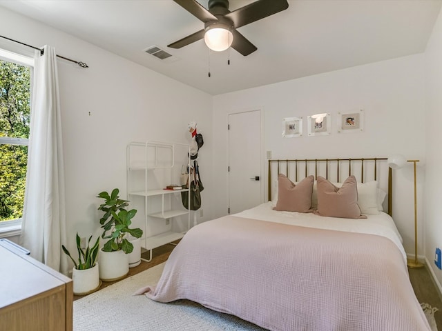 bedroom featuring multiple windows, hardwood / wood-style floors, and ceiling fan