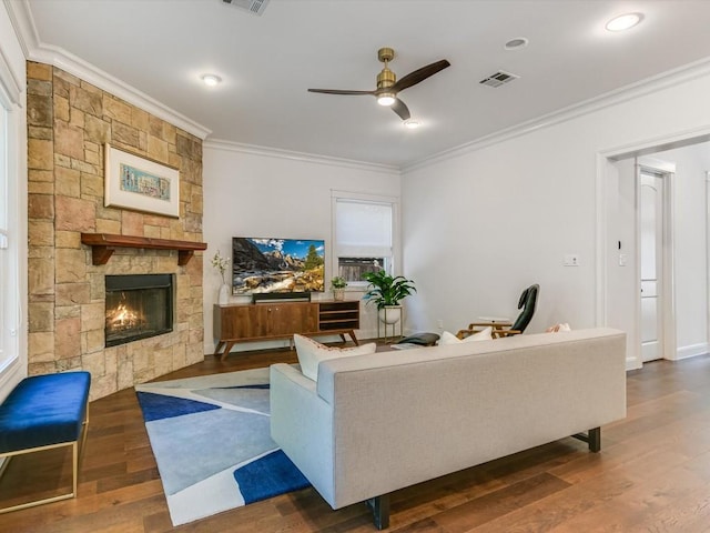 living room featuring a stone fireplace, ceiling fan, dark hardwood / wood-style floors, and ornamental molding