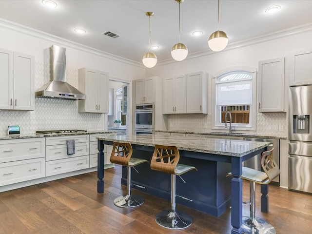 kitchen with a kitchen breakfast bar, stainless steel appliances, light stone counters, and wall chimney range hood