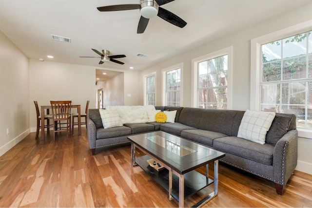 living room with wood-type flooring, ceiling fan, and a healthy amount of sunlight