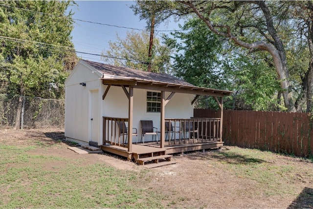 rear view of house featuring an outdoor structure, a wooden deck, and a lawn