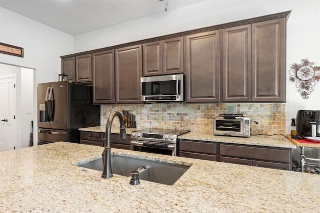 kitchen with appliances with stainless steel finishes, decorative backsplash, sink, and dark brown cabinets