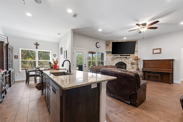 kitchen with sink, light wood-type flooring, plenty of natural light, and an island with sink