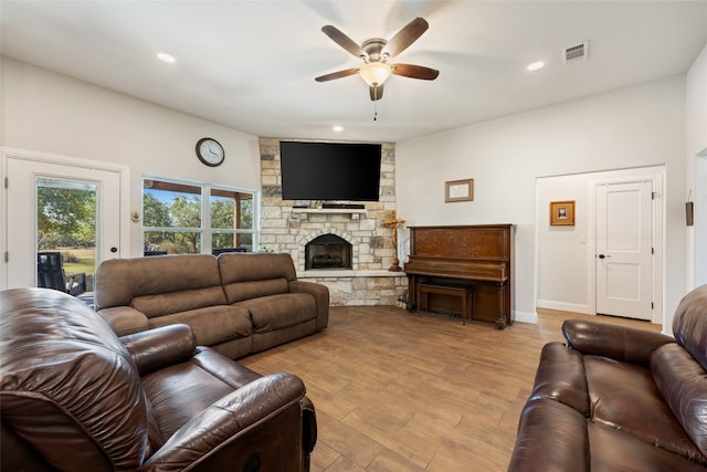 living room featuring a fireplace, light hardwood / wood-style floors, and ceiling fan