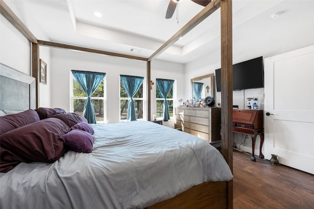 bedroom featuring ceiling fan, a tray ceiling, and dark hardwood / wood-style flooring