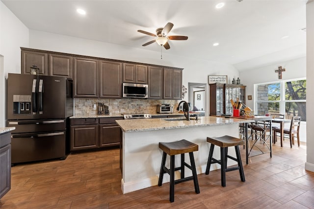 kitchen featuring dark brown cabinets, appliances with stainless steel finishes, dark hardwood / wood-style flooring, and a kitchen island with sink