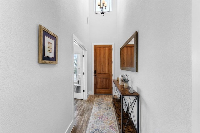 hall featuring light hardwood / wood-style flooring and a notable chandelier