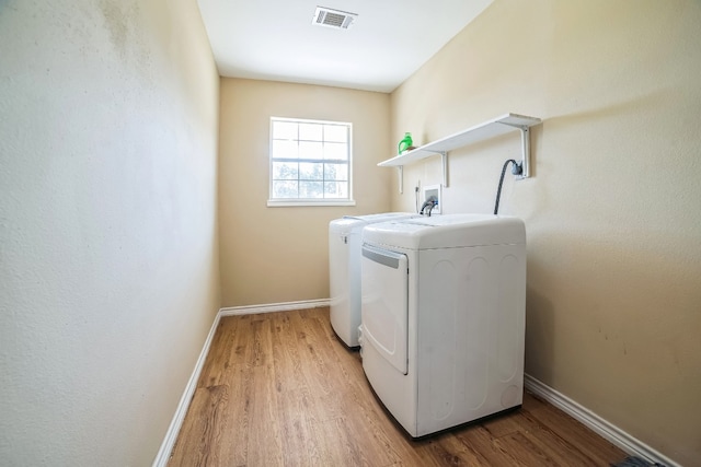 washroom featuring washer and clothes dryer and light hardwood / wood-style floors