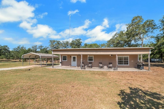 back of house with a carport, ceiling fan, a patio, and a lawn