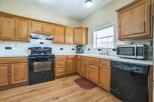 kitchen with decorative backsplash, sink, black appliances, and light hardwood / wood-style floors