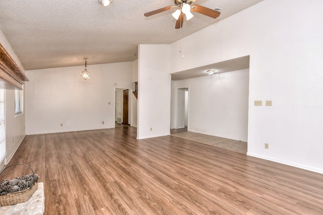 unfurnished living room with ceiling fan with notable chandelier, wood-type flooring, a textured ceiling, and vaulted ceiling