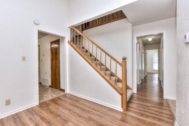 staircase with wood-type flooring and a textured ceiling