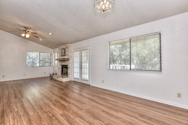 unfurnished living room with a fireplace, a textured ceiling, vaulted ceiling, and ceiling fan with notable chandelier