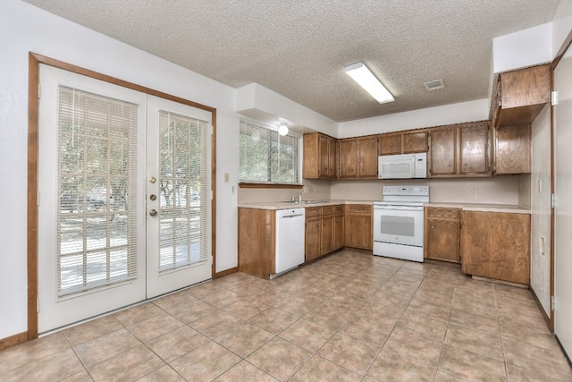 kitchen featuring white appliances, french doors, sink, light tile patterned floors, and a textured ceiling