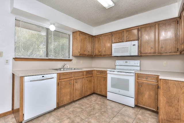 kitchen featuring a textured ceiling, light tile patterned flooring, white appliances, and sink