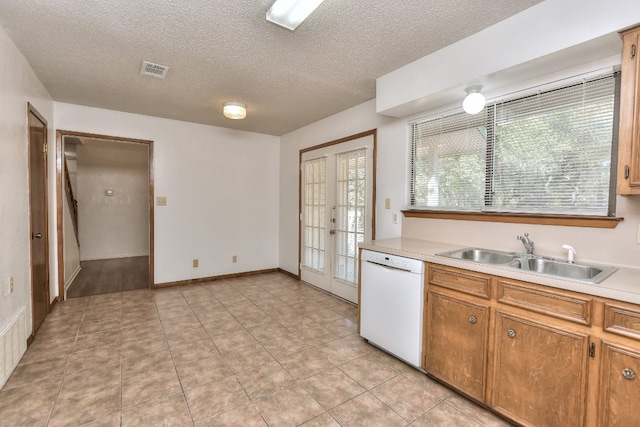 kitchen featuring dishwasher, french doors, sink, a textured ceiling, and light tile patterned flooring