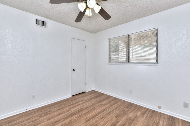 empty room with a textured ceiling, hardwood / wood-style flooring, and ceiling fan