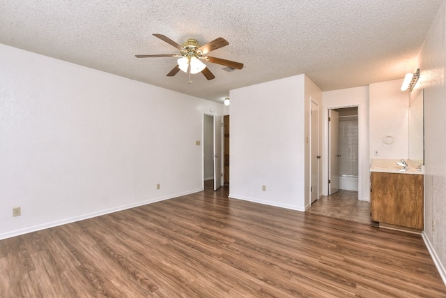 unfurnished bedroom featuring ceiling fan, dark hardwood / wood-style flooring, a textured ceiling, and connected bathroom