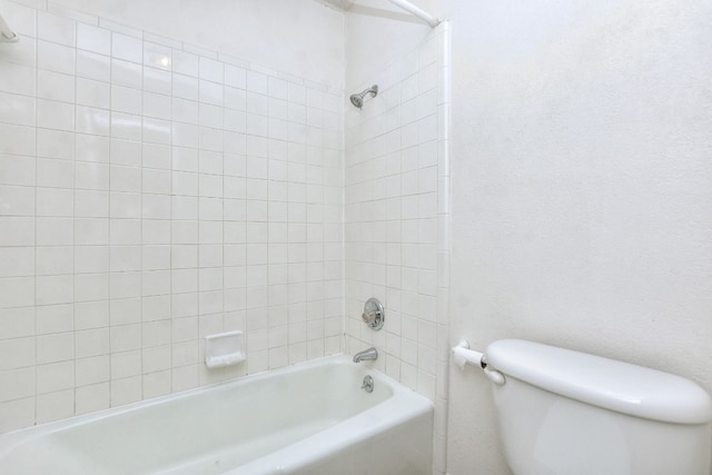 bathroom featuring toilet and tiled shower / bath