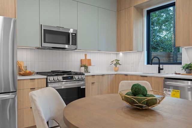 kitchen featuring backsplash, stainless steel appliances, sink, and white cabinets