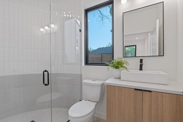 bathroom with a shower with door, vanity, toilet, and a wealth of natural light