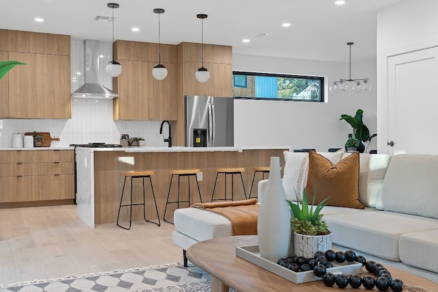 2704 Canterbury St Unit A, Austin, TX 78702 - kitchen featuring a breakfast bar, wall chimney exhaust hood, stainless steel refrigerator with ice dispenser, modern cabinets, and tasteful backsplash