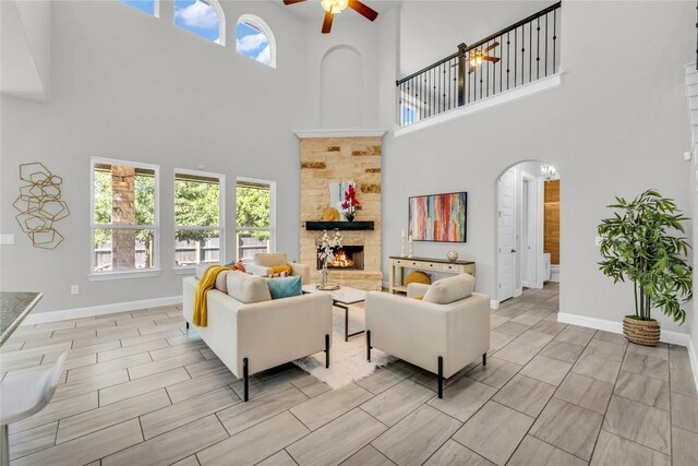 110 Magona Trl, Georgetown, TX 78628 - living area featuring a towering ceiling, ceiling fan, baseboards, a fireplace, and arched walkways
