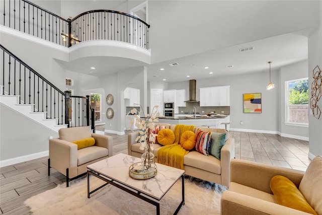 living room featuring sink, light hardwood / wood-style flooring, and a towering ceiling