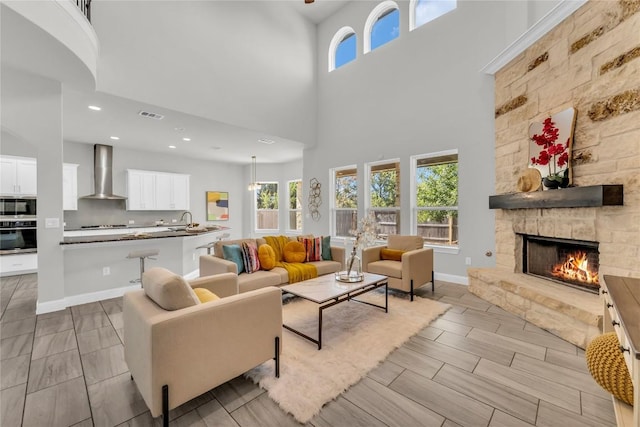110 Magona Trl, Georgetown, TX 78628 - living room featuring a stone fireplace, wood tiled floor, a high ceiling, and a healthy amount of sunlight