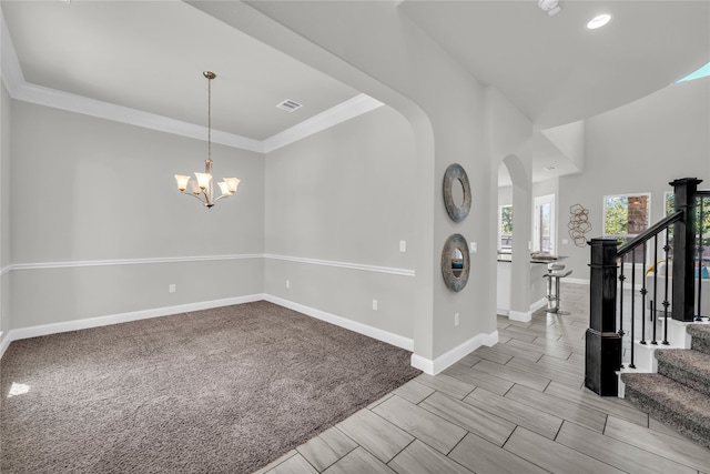 interior space with light carpet, crown molding, and a chandelier