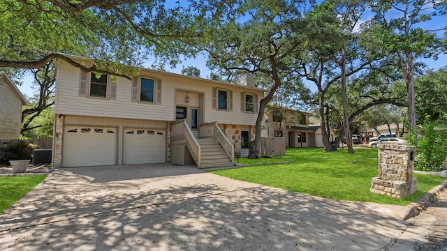 raised ranch with central AC unit, a front lawn, and a garage