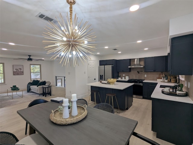 dining area featuring ceiling fan with notable chandelier, light hardwood / wood-style floors, and sink