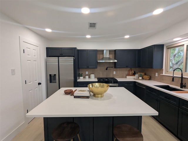 kitchen featuring wall chimney exhaust hood, a center island, stainless steel fridge, a breakfast bar area, and sink