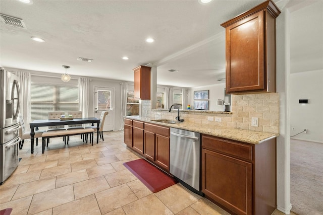 kitchen with backsplash, appliances with stainless steel finishes, light stone countertops, pendant lighting, and sink