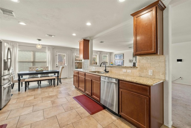 104 Bufflehead Ln, Leander, TX 78641 - kitchen featuring stainless steel appliances, a sink, backsplash, light stone counters, and brown cabinets