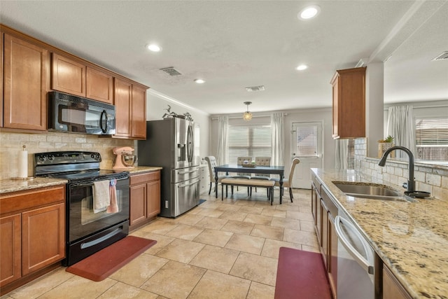 kitchen featuring hanging light fixtures, light stone counters, backsplash, black appliances, and sink