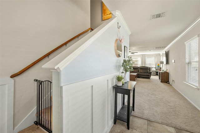 hall with crown molding and light carpet