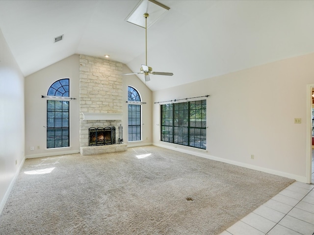 unfurnished living room featuring light carpet, a stone fireplace, vaulted ceiling, and ceiling fan