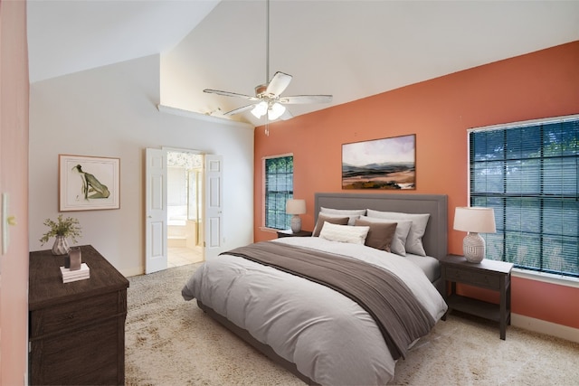 carpeted bedroom featuring multiple windows, ensuite bath, high vaulted ceiling, and ceiling fan