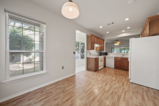 kitchen with white appliances, sink, hanging light fixtures, ceiling fan, and light wood-type flooring