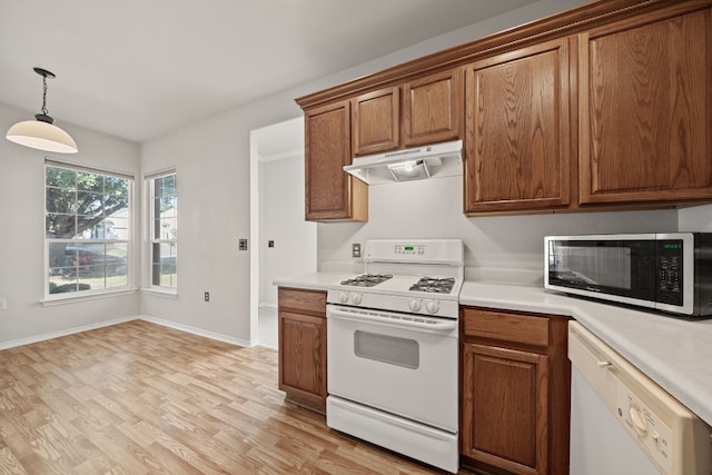 kitchen featuring white appliances, hanging light fixtures, and light hardwood / wood-style flooring