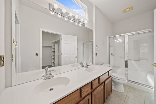 bathroom featuring tile patterned flooring, vanity, a shower with shower door, and toilet