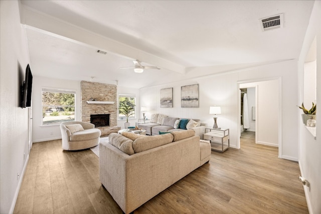 living room with ceiling fan, a fireplace, light hardwood / wood-style flooring, and vaulted ceiling with beams