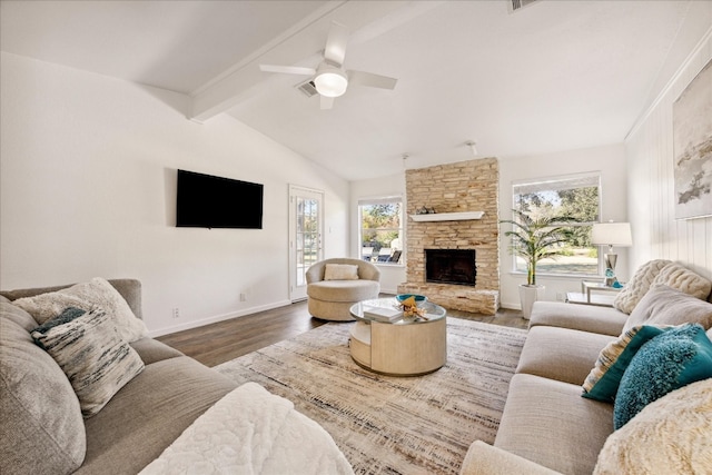 living room featuring vaulted ceiling with beams, a stone fireplace, hardwood / wood-style floors, and ceiling fan