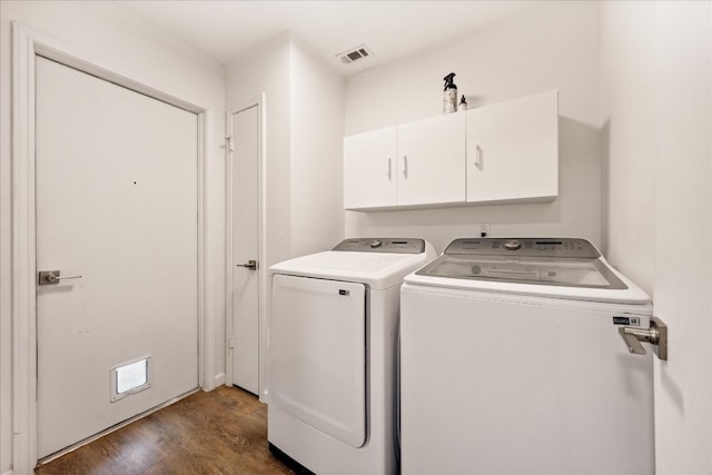 clothes washing area featuring dark wood-type flooring, cabinets, and washing machine and dryer