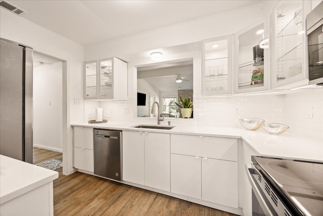 kitchen with tasteful backsplash, white cabinetry, sink, dark hardwood / wood-style flooring, and stainless steel appliances