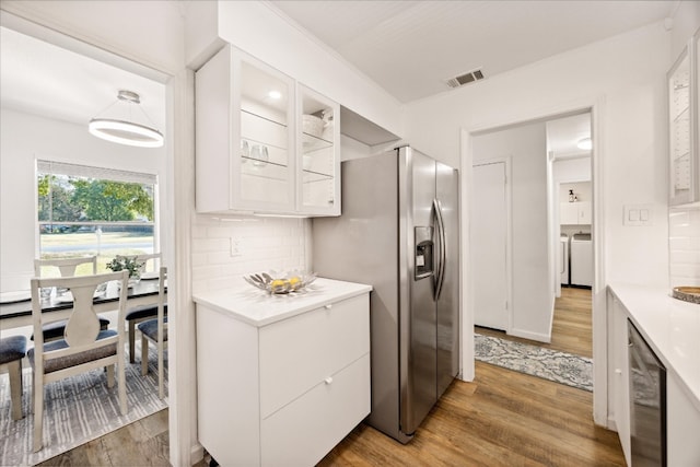 kitchen with white cabinetry, dark hardwood / wood-style floors, stainless steel fridge, and decorative backsplash