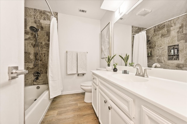 full bathroom featuring hardwood / wood-style flooring, vanity, shower / bathtub combination with curtain, and toilet