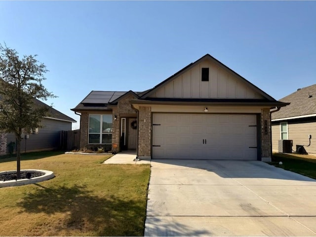 view of front of home featuring central air condition unit, solar panels, a front yard, and a garage