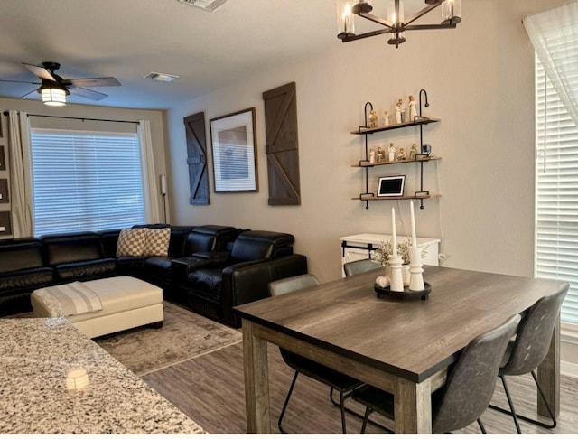 dining space with hardwood / wood-style floors and ceiling fan with notable chandelier